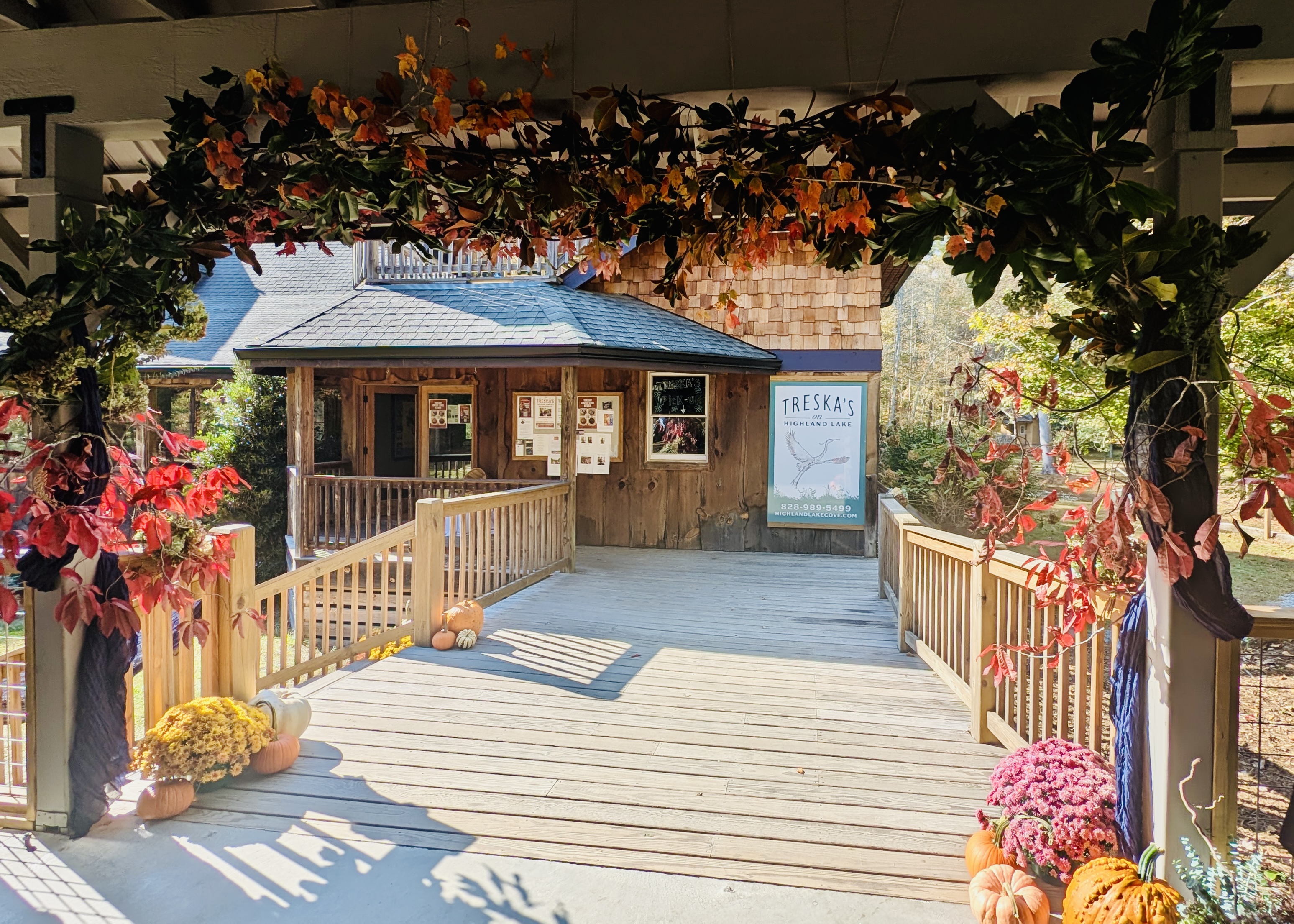 An entry pergola dressed in autumn garland with mums and pumpkins