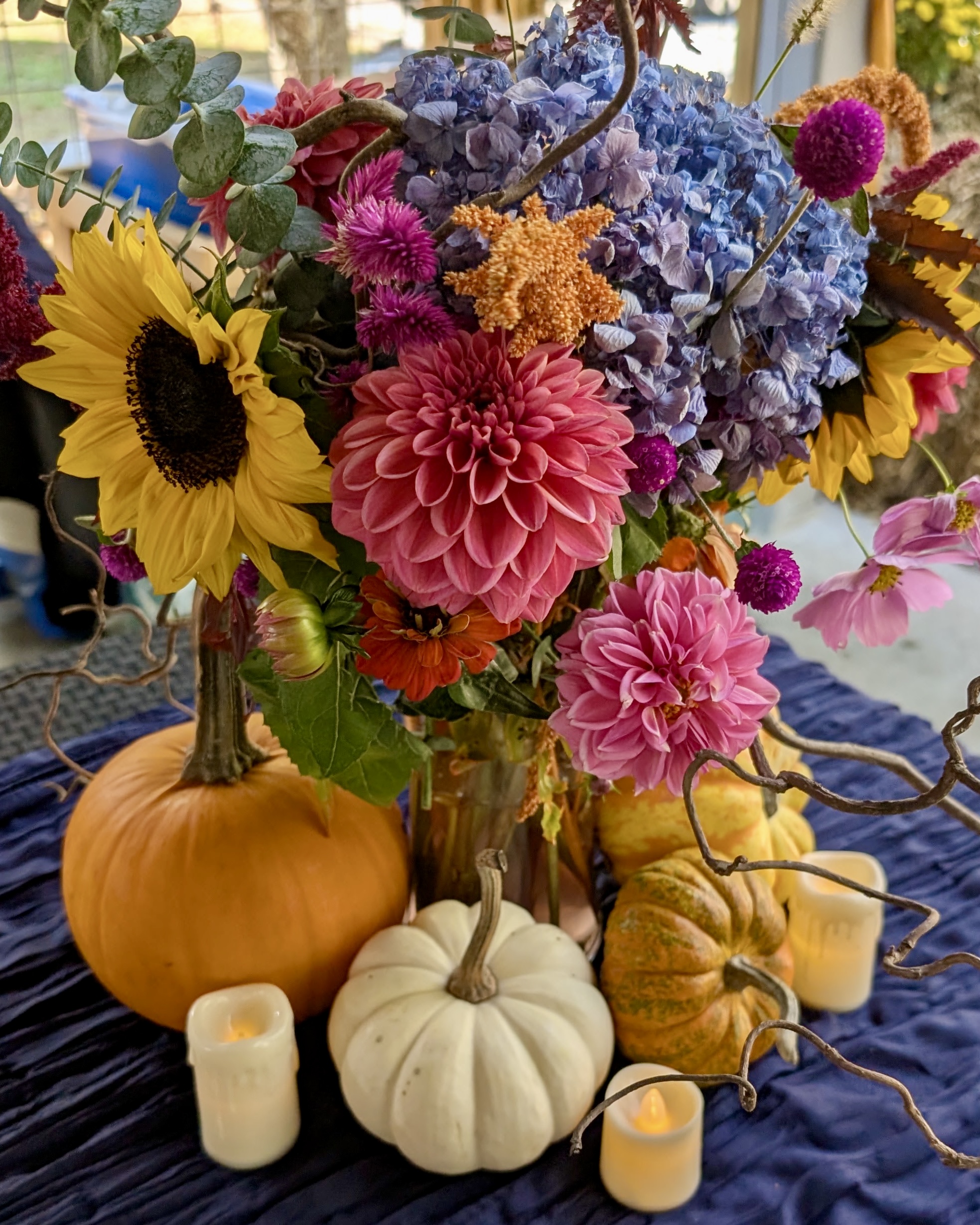 An autumn centerpiece of sunflowers, dahlias, hydrangea, and pumpkins by Marina Johnston Interior Design