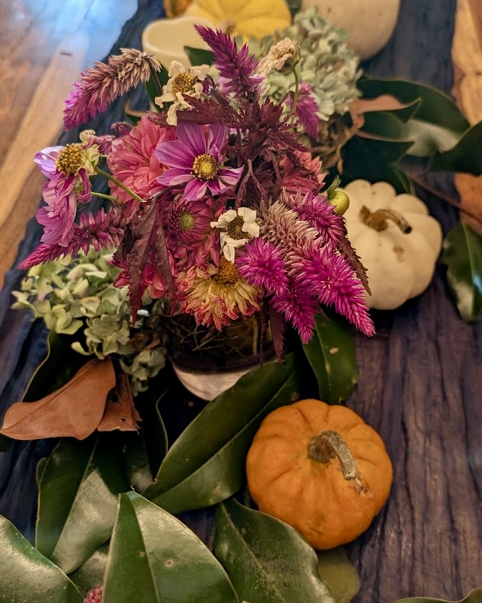 Celosia, dahlias, and cosmos gathered with magnolia leaves and pumpkins